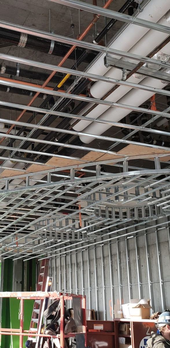 Curved steel ceiling framing threading around mechanical services