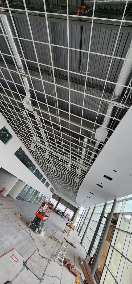 Finished curved drywall soffit meeting a suspended ceiling grid in a tall atrium