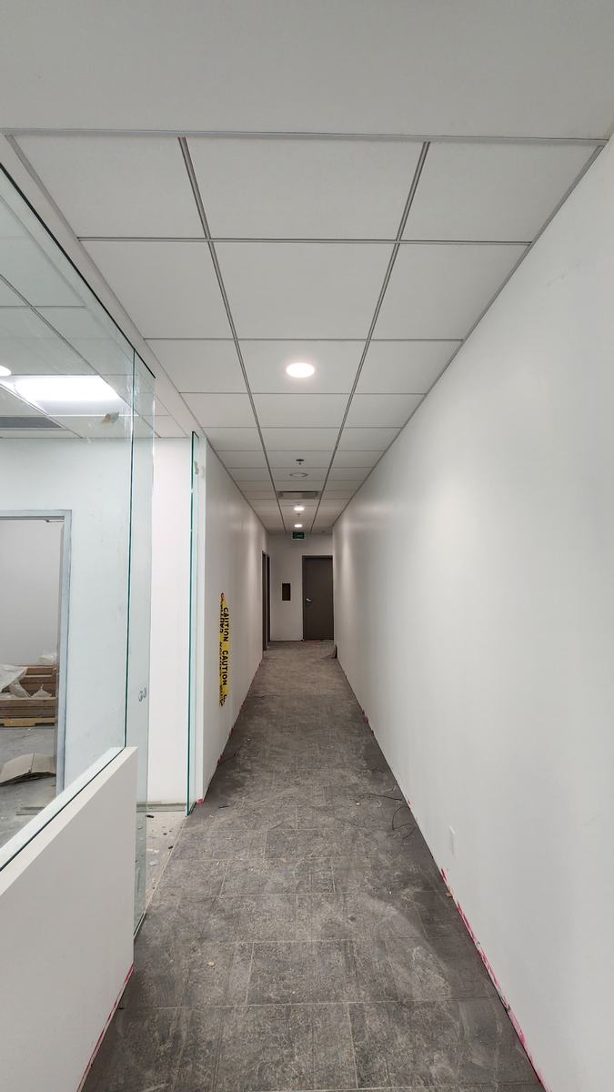 Finished corridor with suspended ceiling grid and glazed partitions