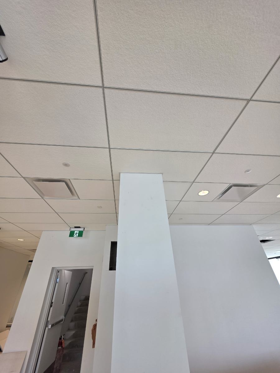 Finished ceiling grid and painted drywall column in a completed commercial interior
