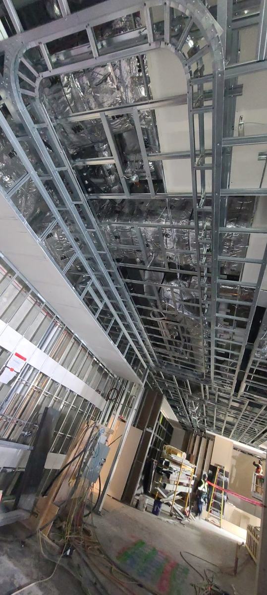 Curved steel stud ceiling bulkhead framed above an open floor